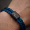 Wave Wellen Armband aus graviertem Edelstahl und blauen Segeltau. Ein besonderes Meeresschutz Armband, auch perfekt als Suferarmband oder als maritimes Geschenk.