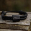 Wave Wellen Armband aus graviertem Edelstahl und schwarzem Segeltau. Ein besonderes Meeresschutz Armband, auch perfekt als Suferarmband oder als maritimes Geschenk.